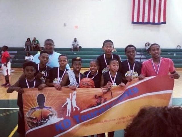 Young Domination players with medals behind a tournament banner