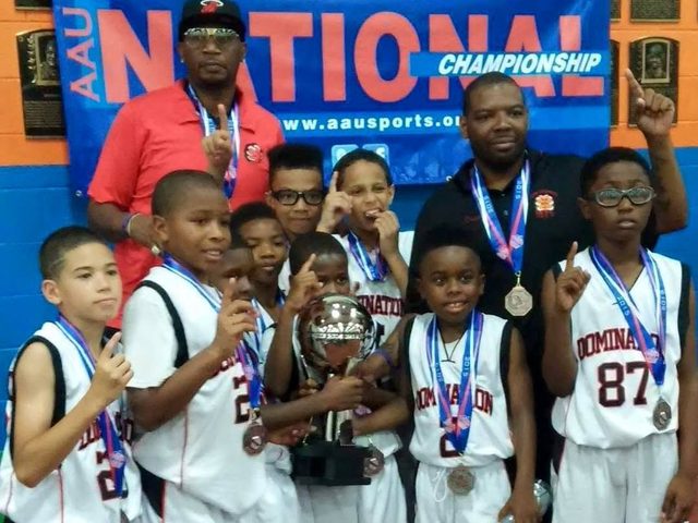 Young Domination players with medals and a trophy in front of an AAU banner