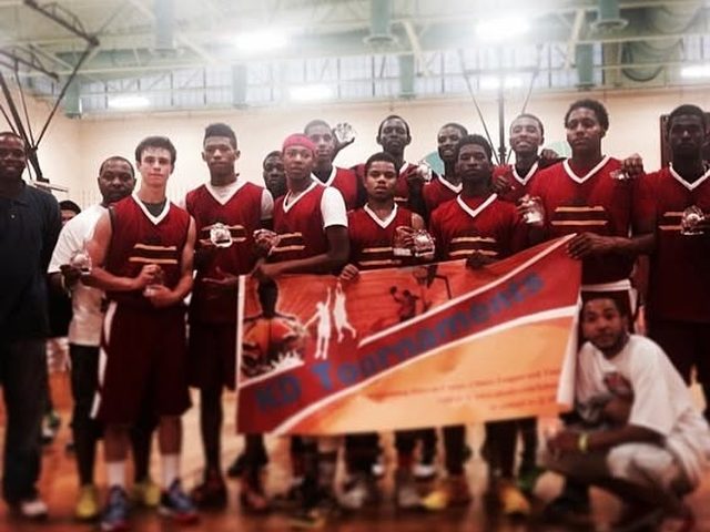 Domination players in maroon with trophies behind a tournament banner