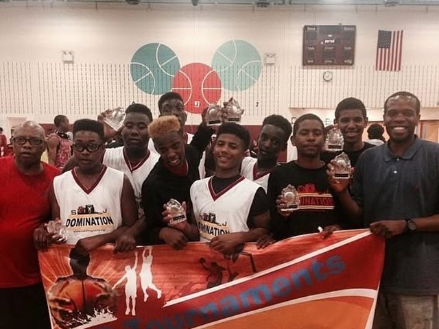 SJ Domination players holding trophies behind a tournament banner